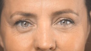 Macro fotografia focada nos olhos expressivos e maduros de uma mulher sorrindo, representando a recuperação da visão e o tratamento da presbiopia após os 55 anos.