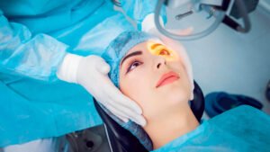 Paciente deitada em ambiente cirúrgico enquanto um médico de luvas realiza os procedimentos preparatórios para a cirurgia ocular. Imagem de capa explicativa sobre a estabilidade do grau pós-operatório.